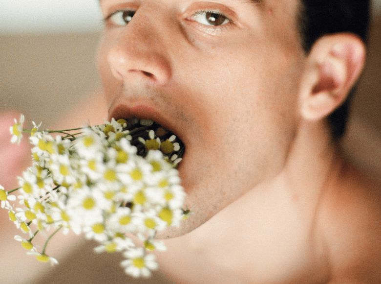 Deep Throat Tipps für Empfänger. Symbolbild: Ein Mann steckt sich einen Strauß Blumen tief in den Hals und schaut lüstern. Englisch: Deep throat tips for recipients. Symbolic image: A man sticks a bunch of flowers deep down his throat and looks lustfully.