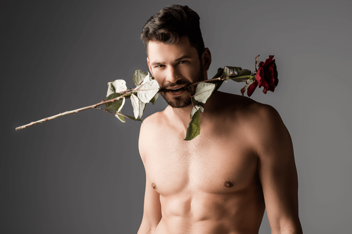 Analprolaps und Rosebud. Symbolbild: Mann mit nacktem Oberkörper trägt eine Rose im Mund. Englisch: Anal prolapse and rosebud. Symbolic image: Man with a naked upper body wearing a rose in his mouth.