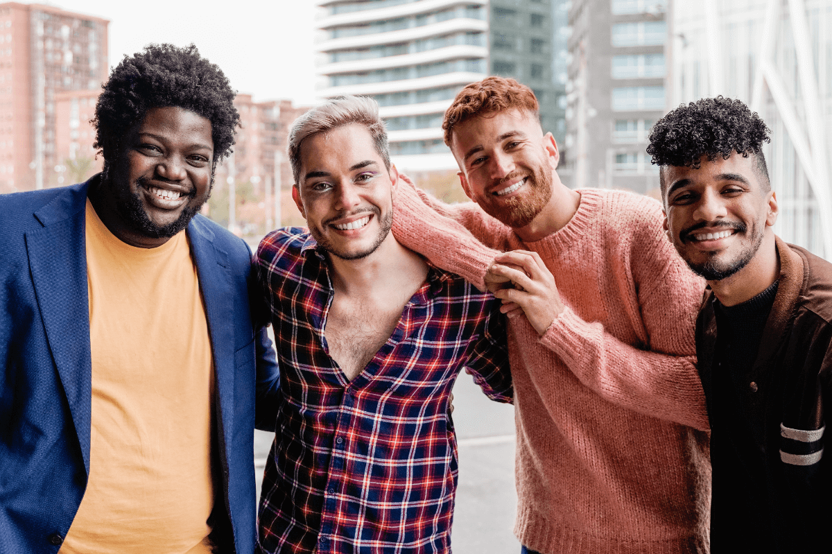 Männergruppe Symbolbild: 4 Männer unterschiedlicher Hautfarbe, Gewicht usw. lachen in die Kamera. Englisch: Men's Groups Symbolic image: 4 men of different skin color, weight, etc. laughing into the camera.