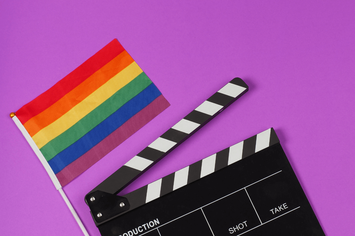 Queere Filme. Symbolbild: Filmklappe und Regenbogenfahne. Englisch: Queer movies Symbolic image: movie flap and rainbow flag.