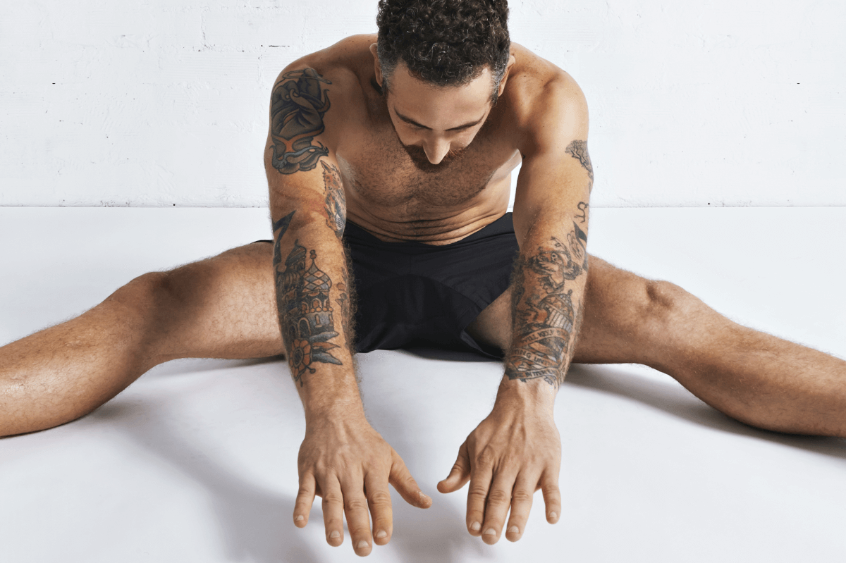 Autofellatio Symbolbild: Ein an den Armen tätowierter Mann, der nur mit Unterhose bekleidet ist, macht Dehnübungen. Englisch: Self-sucking symbol picture: a man tattooed on his arms, wearing only underpants, does stretching exercises.