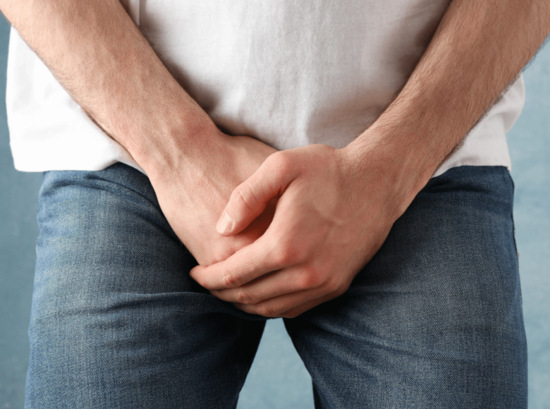 Priapismus Symbolbild: Ein Mann hält sich die Hände vors Geschlechtsteil. Englisch: Priapism: a man covering his genitals with his hands.