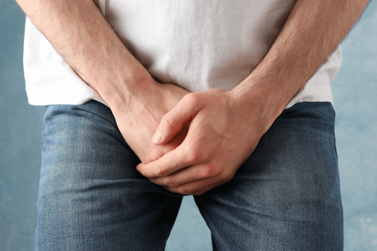 Priapismus Symbolbild: Ein Mann hält sich die Hände vors Geschlechtsteil. Englisch: Priapism: a man covering his genitals with his hands.