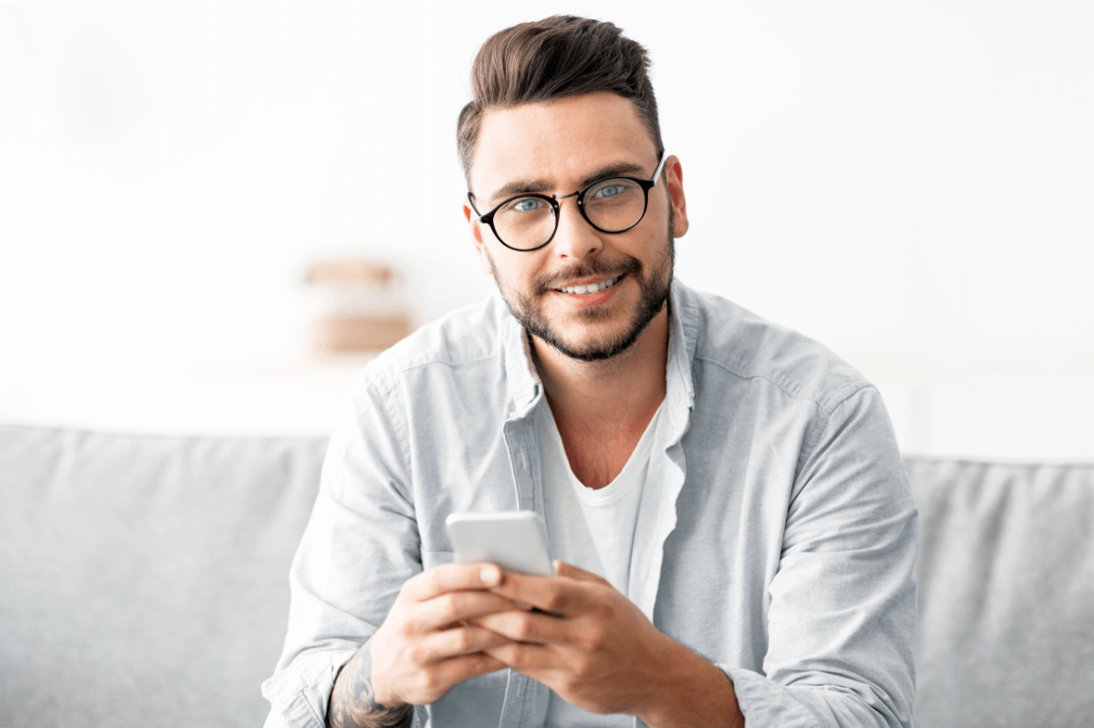 Gesunder Gebrauch einer Dating-App Symbolbild: Ein junger Mann lächelt in die Kamera. Englisch: Healthy use of dating apps. Symbolic image: a young man smiles at the camera.