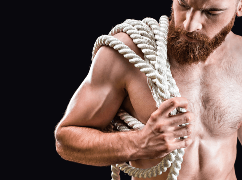Rigger BDSM oder Rope Top. Symbolbild: Ein Mann mit freiem Oberkörper trägt ein dickes Seil. Englisch: Rigger or rope top. Symbolic image: a shirtless man carries a thick rope.