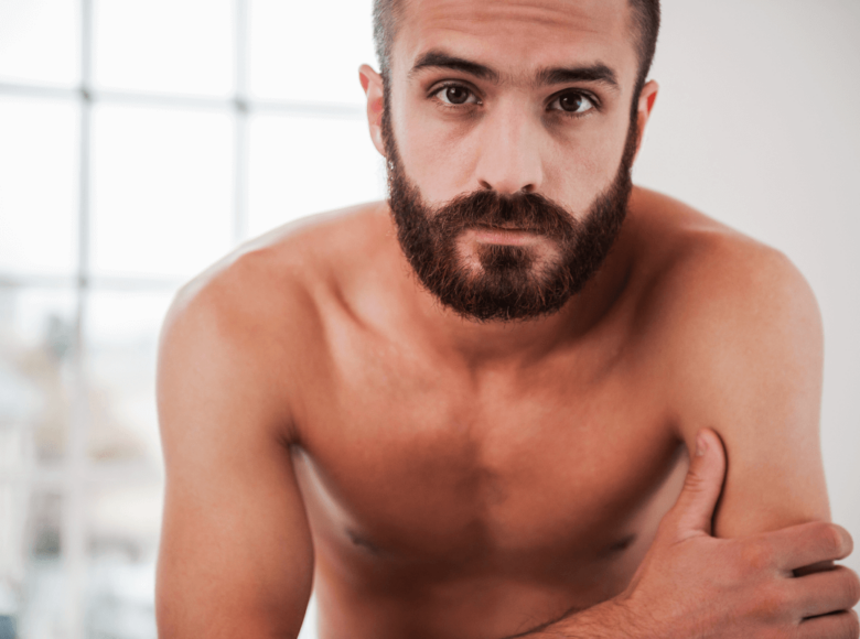 Side kein Anal - Symbolbild: Ein Mann mit nacktem Oberkörper schaut ernst in die Kamera. Englisch: Side no anal - Symbolbild: A man with a naked torso looks seriously into the camera.