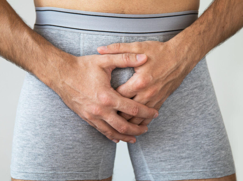 Beschneidung Symbolbild: Bildausschnitt eines männlichen Genitalbereichs in Unterhose, bei dem die Hände vor das Geschlechtsteil gelegt sind. Englisch: Circumcision Symbolic image: detail of a male genital area in underpants, with the hands placed in front of the genitals.