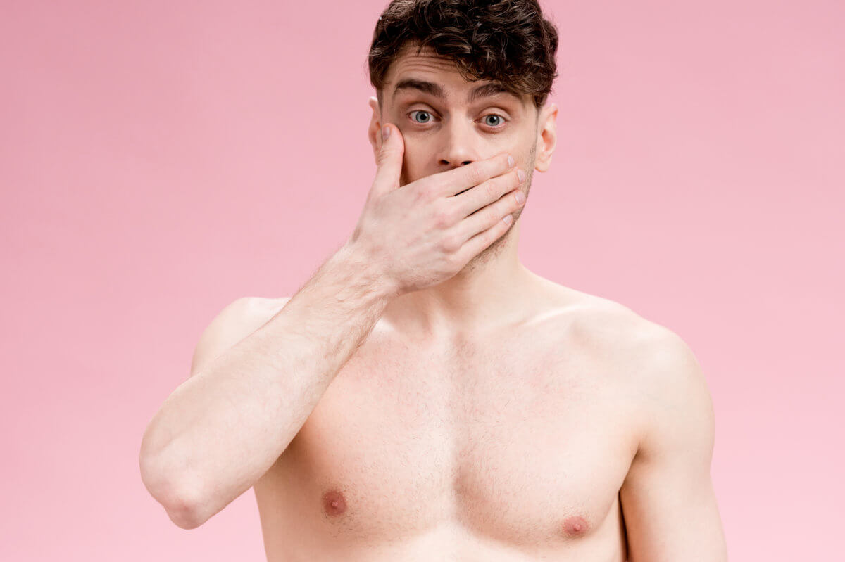 Angstspiele: Ein Mann mit freiem Oberkörper hält sich vor Entsetzen die Hand vor den Mund. Englisch: Fear play: A man with his upper body exposed covers his mouth in horror.