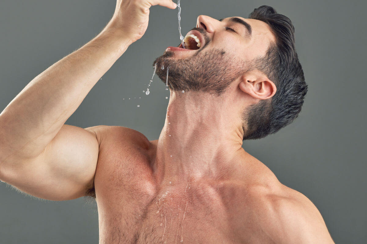 Gagging Symbolbild: Ein Mann mit nacktem Oberkörper lässt sich Wasser tief in den Hals tropfen.