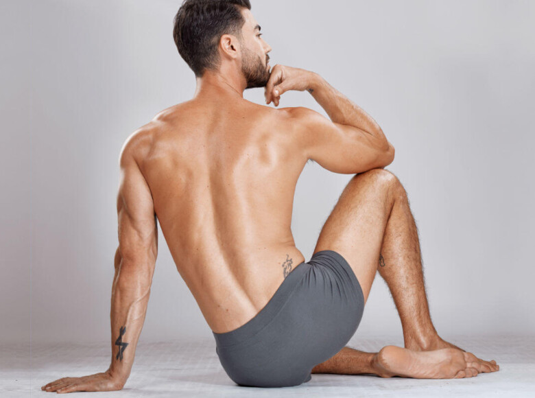 Prostatamassage Symbolbild: Ein Mann, nur mit Unterhose bekleidet, sitzt mit dem Rücken zur Kamera auf dem Boden. Englisch: Prostate massage Symbolic image: A man wearing only underwear is sitting on the floor with his back to the camera.