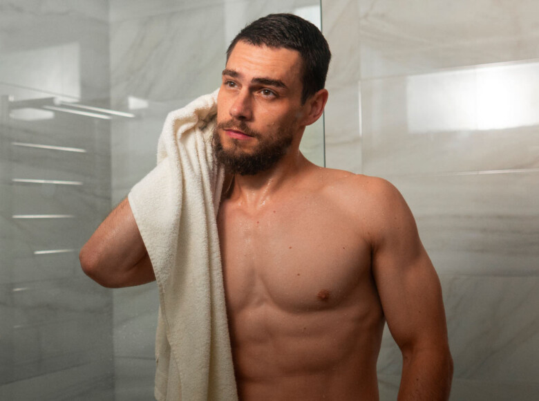 Analsex Reinigung Symbolbild: ein Mann kommt aus der Dusche und trocknet sich mit dem Handtuch ab. Englisch: Anal sex cleaning Symbolic image: a man comes out of the shower and dries himself with a towel.