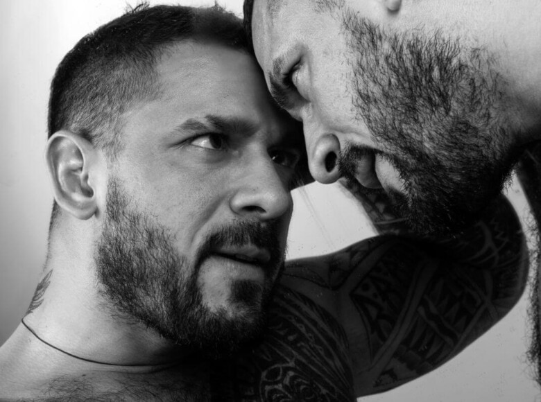 BDSM-Prinzipien Symbolbild: Schwarz-Weiß-Bild. Zwei Männer halten die Köpfe zusammen und sehen sich intensiv in die Augen. BDSM principles Symbolic image: Black and white image. Two men hold their heads together and look intensely into each other's eyes.