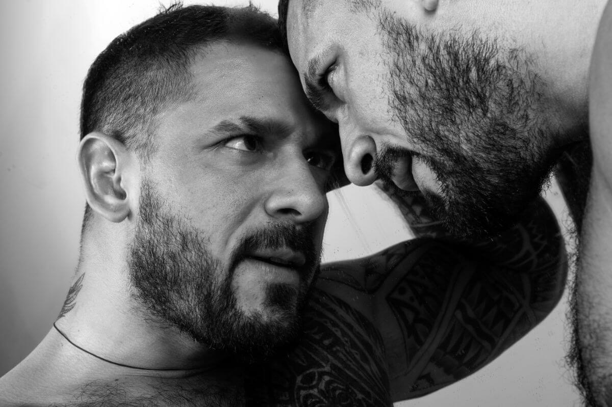 BDSM-Prinzipien Symbolbild: Schwarz-Weiß-Bild. Zwei Männer halten die Köpfe zusammen und sehen sich intensiv in die Augen. BDSM principles Symbolic image: Black and white image. Two men hold their heads together and look intensely into each other's eyes.