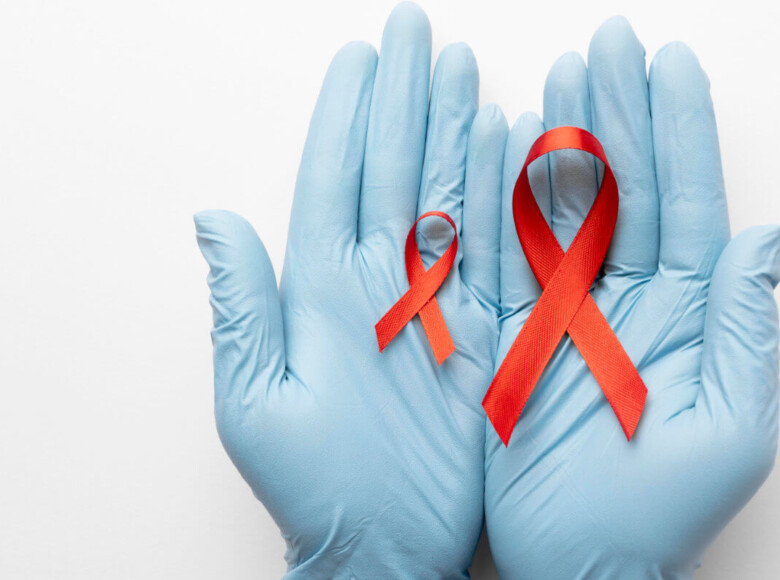 TasP Symbolbild: Zwei Hände mit medizinischen Handschuhen halten eine große und eine kleine Aids-Schleife. TasP Symbolic image: Two hands wearing medical gloves hold a large and a small AIDS ribbon.