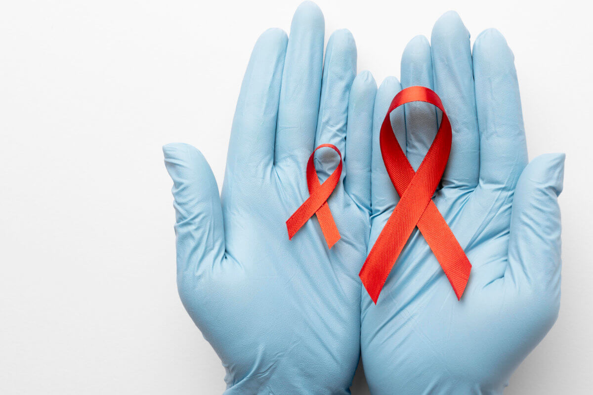 TasP Symbolbild: Zwei Hände mit medizinischen Handschuhen halten eine große und eine kleine Aids-Schleife. TasP Symbolic image: Two hands wearing medical gloves hold a large and a small AIDS ribbon.