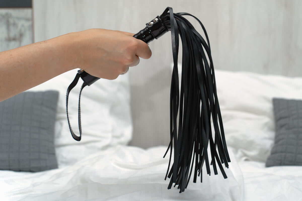 BDSM Geschichte Spanking, Paddling, Peitsche: Symbolbild eine schwarze Peitsche / Flogger. BDSM History Spanking, paddling, whipping: Symbolic image of a black whip/flogger.